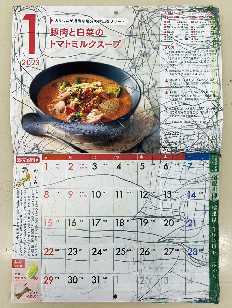 【写真】2023年1月のカレンダー全面。上部には「豚肉と白菜のトマトミルクスープ」の料理写真とレシピ、下部にはカレンダーの表が掲載されている。鉛筆の線が「1月」の「1」の字のまわりなどを囲んで縦横に走り、表の木、金、土曜3列分のスペースを使って「歯医者」の文字が書かれている。