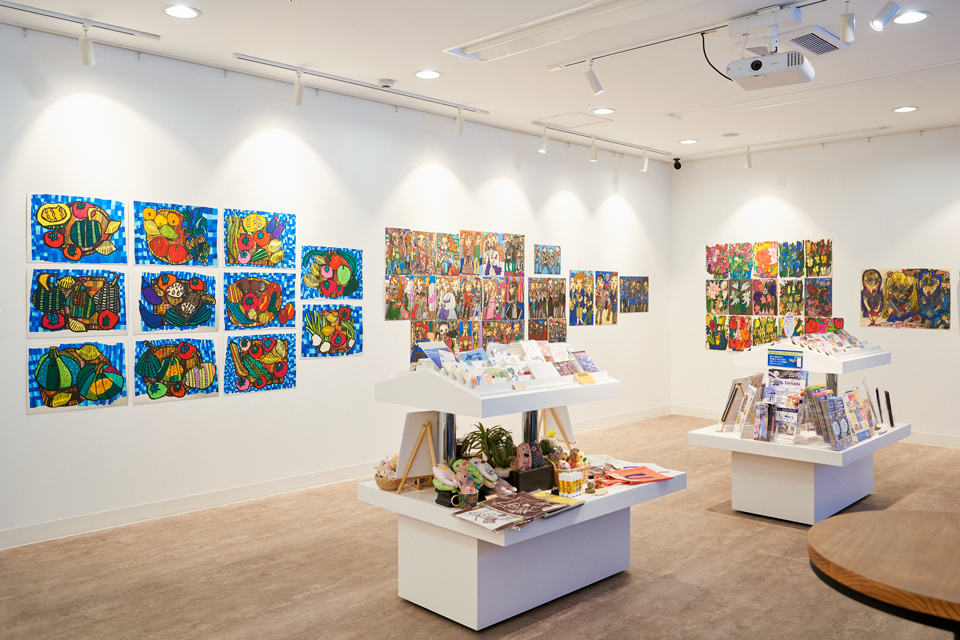 【写真】札幌市内での個展の展示風景。会場の白い壁には、色鮮やかな田湯加那子さんの作品が展示されている。